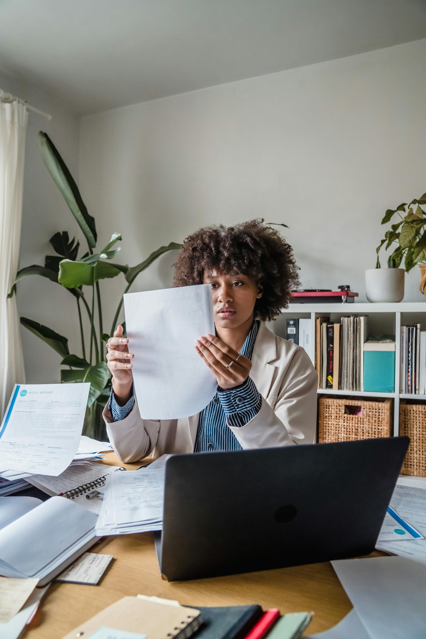 Woman working remotely with documents, focusing on office tasks at a desk.