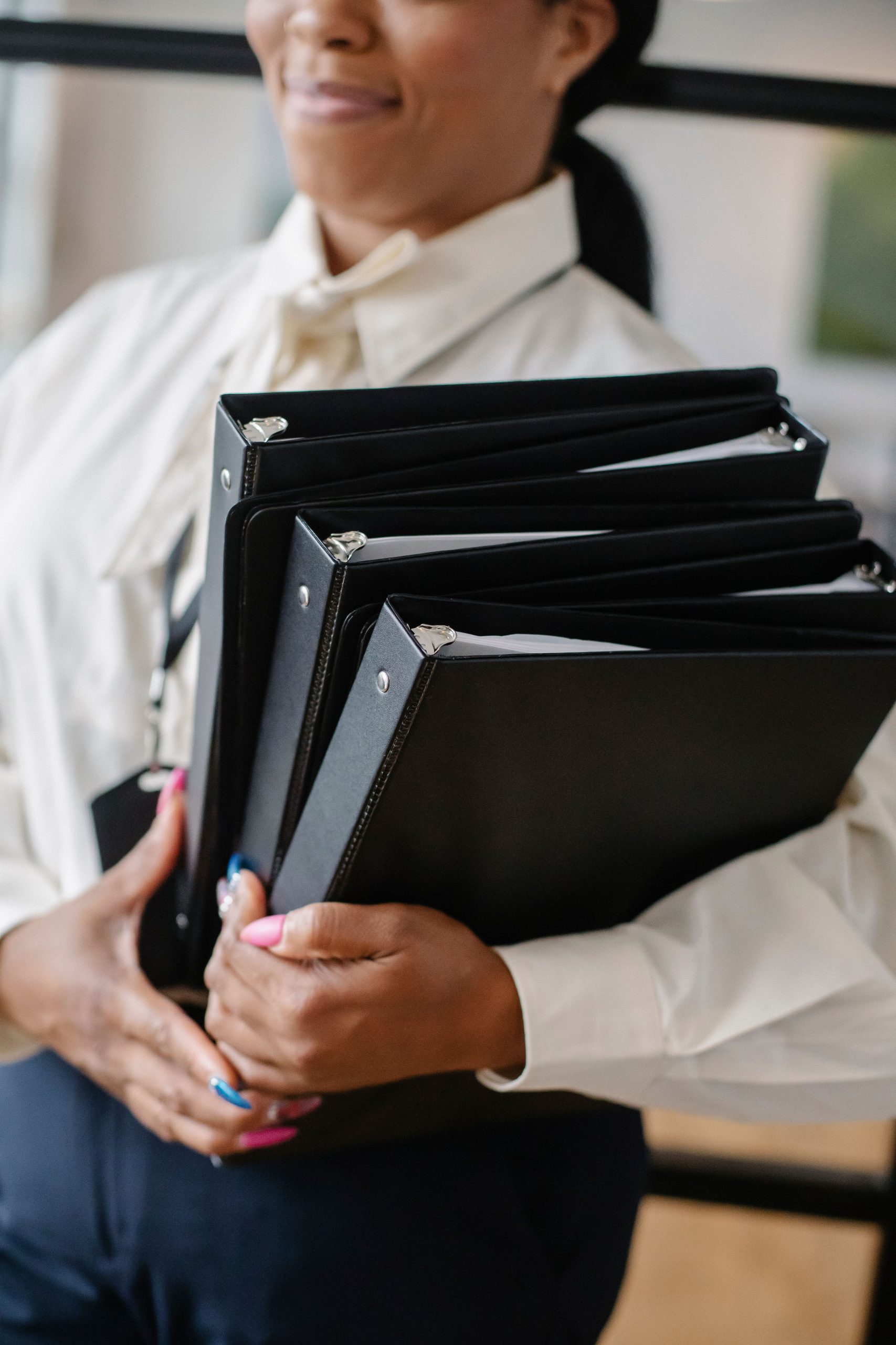 Crop African American businesswoman with folders of documents and files standing in office room